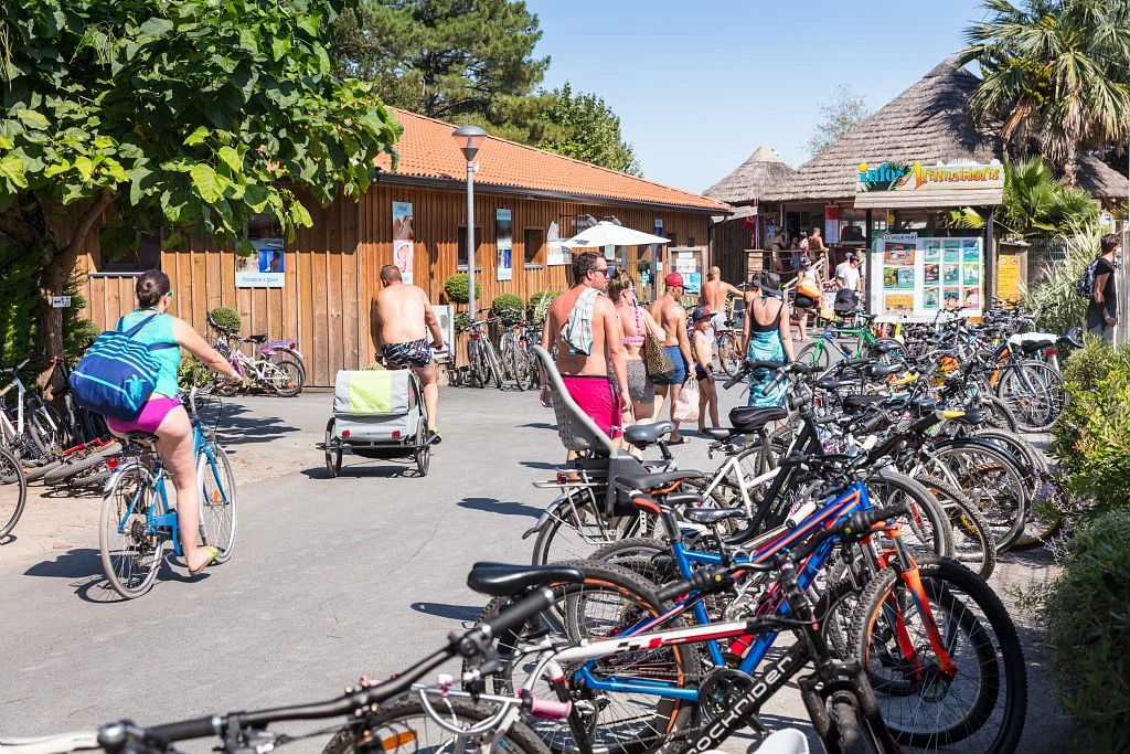 At Le Vieux Port, individuals are strolling and cycling near a timber structure with bicycles tightly arranged in racks.