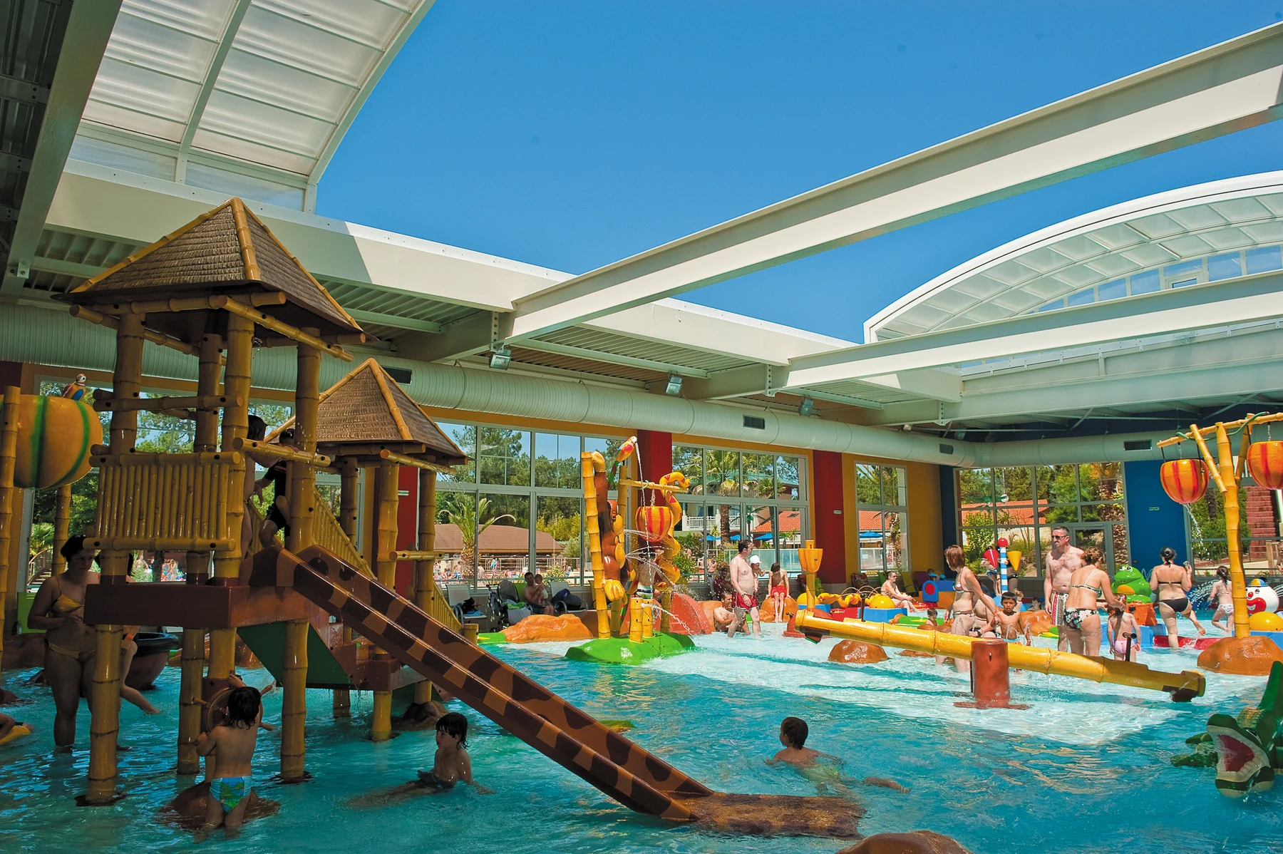 At Sylvamar, kids and adults enjoy activities in an indoor aquatic park featuring slides, swimming areas, and vibrant decorations.