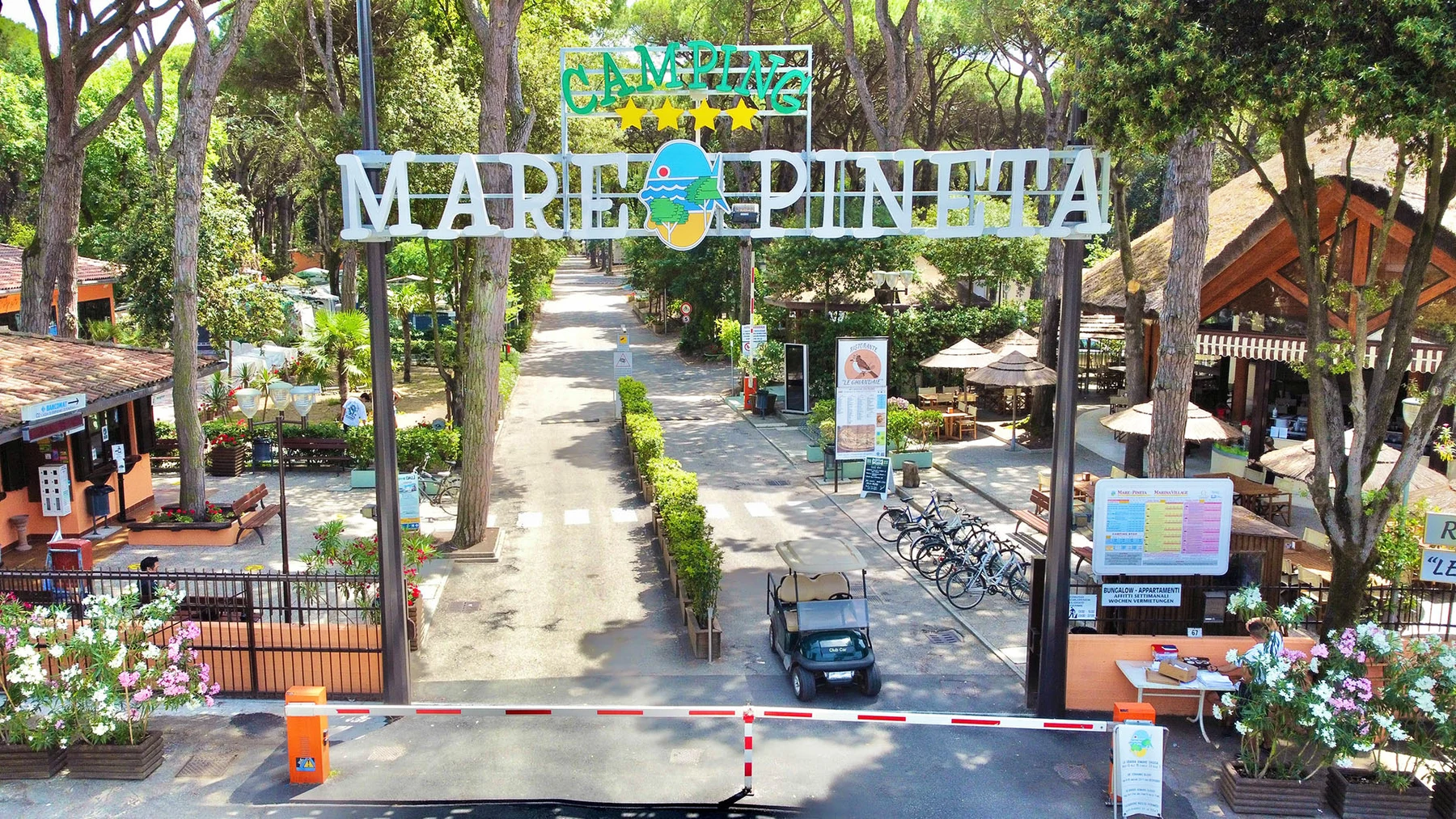 At Mare E Pineta, the entrance greets guests to a verdant campsite featuring cabins and facilities.