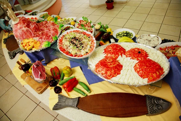 At Isuledda, an array of salads and cold cuts is showcased on a buffet table embellished with fresh produce and decorative elements.