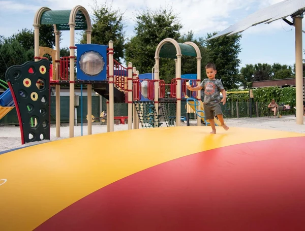 At Recreatieoord Wilhelm Tell, a child dashes across a vast, vibrant inflatable area adjacent to a play area featuring climbing structures and slides.