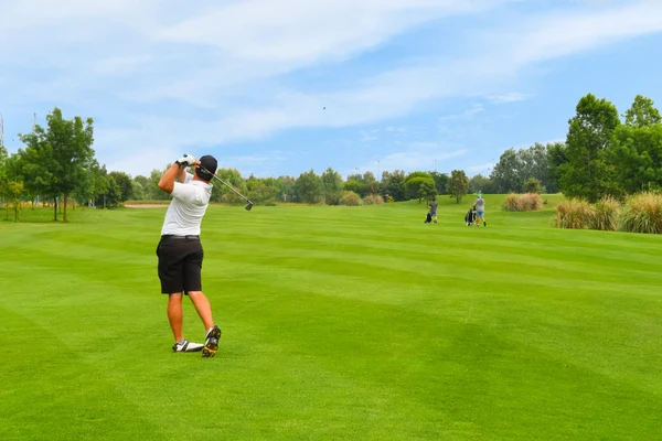 At Pra delle Torri, a golfer swings their club on a vibrant green course, with distant players and trees under a clear blue sky.