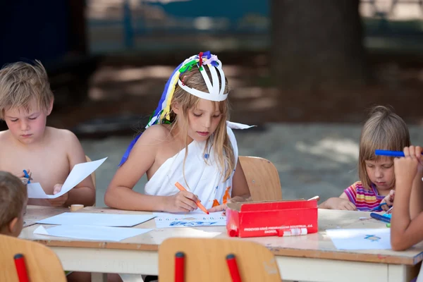At Naturist Park Koversada, children are sketching and creating at a table in an outdoor environment.