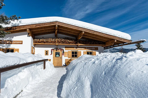 At Eurocamp Wilder Kaiser, a snowy cabin with a wood stack sheltered under a roof is encircled by deep snow.