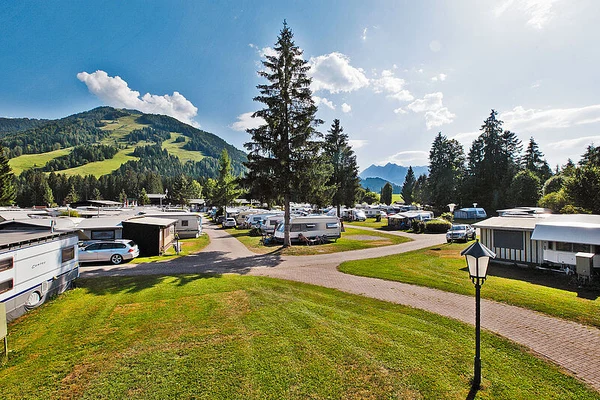 At Eurocamp Wilder Kaiser, caravans are stationed among trees and trails in a vast camping area, with undulating green hills in the backdrop.