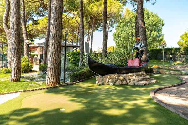 At Marina di Venezia, a figure in a gondola sculpture is positioned among trees, close to a miniature golf course.