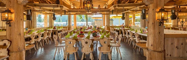 At Eurocamp Wilder Kaiser, wooden dining tables are arranged with green napkins and floral arrangements in a rustic, log-constructed eatery.