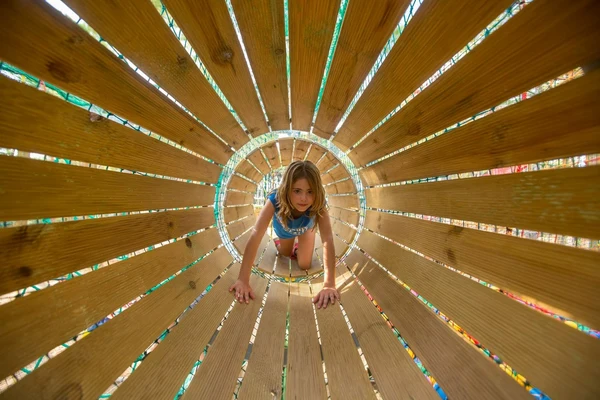 At Ondres Plage, a child is crawling through a wooden tunnel structure enveloped by a vibrant outdoor environment.