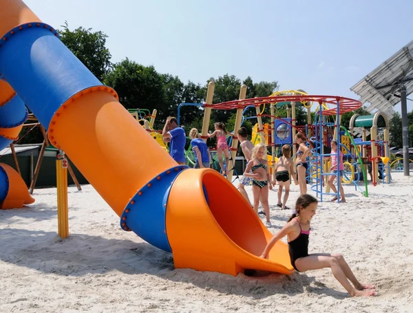 At Recreatieoord Wilhelm Tell, kids enjoy themselves on a play area featuring a big spiral slide and climbing equipment in a sandy outdoor space.