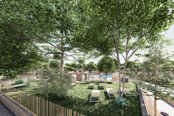 At Ondres Plage, lounge chairs are positioned beneath towering trees next to a enclosed swimming pool, encircled by vibrant foliage.