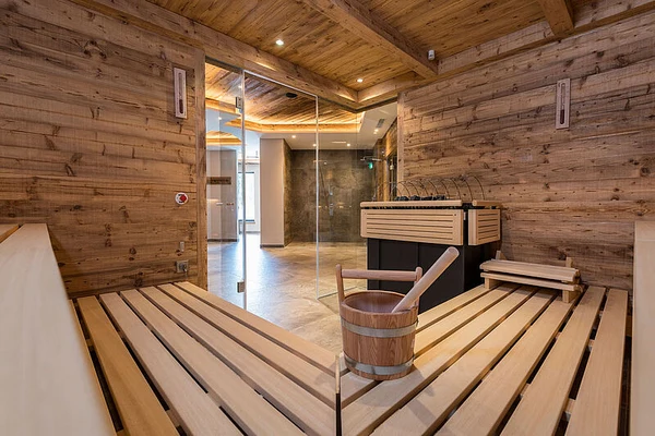 At Eurocamp Wilder Kaiser, there is a wooden sauna chamber featuring seating benches and a bucket, with an outdoor space visible through a glass door.
