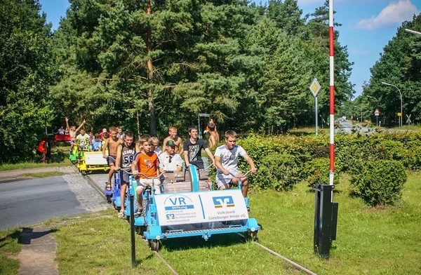 At Knaus Campingpark Bleckede/Elbtalaue, a group of individuals is riding on a rail bike through a verdant forested region.