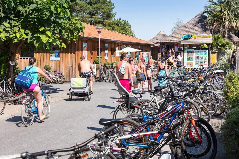 At Le Vieux Port, individuals are strolling and cycling near a timber structure with bicycles tightly arranged in racks.