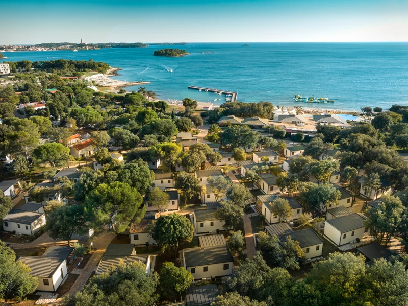 At Amarin, a bird's-eye perspective reveals cabins tucked away among the trees close to the sea, featuring a pier and vessels.